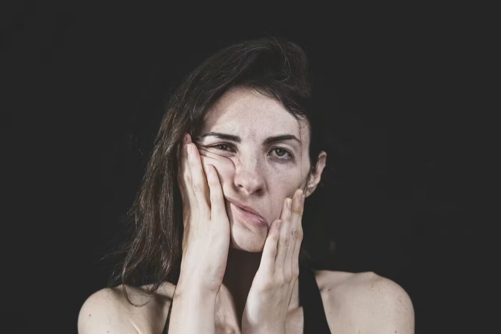 Eine Frau drückt erschöpft ihr Gesicht in die Hände – Ausdruck innerer Anspannung, Überforderung und eines überreizten Nervensystems.