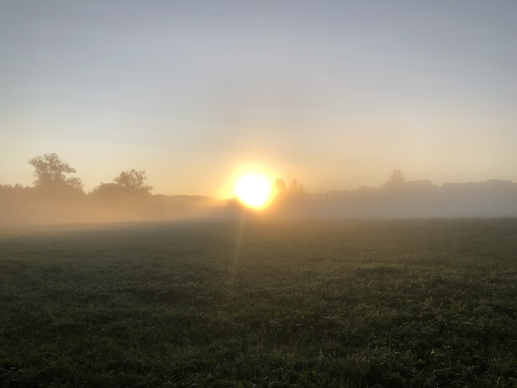Sonnenaufgang über einer nebligen Landschaft am frühen Morgen.